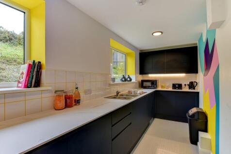 This modern kitchen features sleek black cabine...