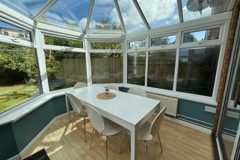 A bright and inviting garden room featuring a s...