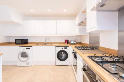 This modern kitchen features sleek white cabine...