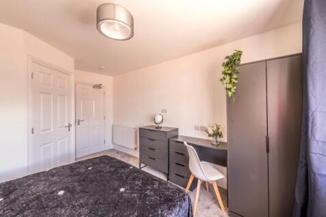 This cozy double bedroom features ample natural...