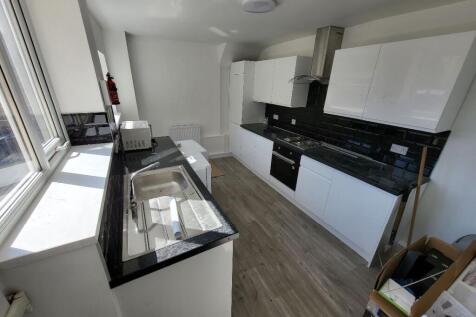 This modern kitchen features sleek white cabine...