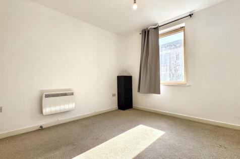 A cozy double bedroom featuring a well-lit wind...