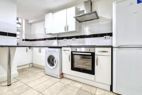 Modern kitchen featuring sleek white cabinetry,...