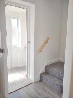Bright hallway featuring a clean carpeted stair...