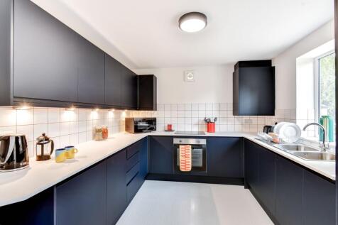 Modern kitchen featuring sleek black cabinetry,...