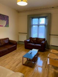 A cozy living room featuring rich wooden floori...