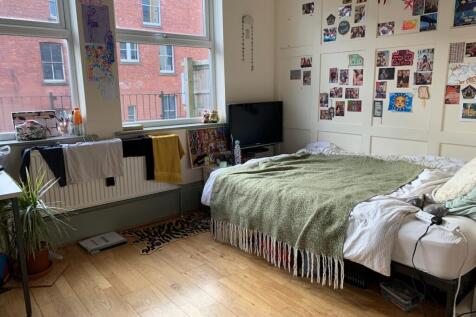 A cozy and well-lit single bedroom featuring a ...