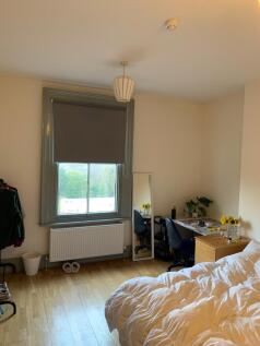 A cozy double bedroom featuring light wooden fl...