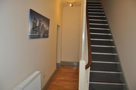 A clean and tidy hallway featuring wooden floor...