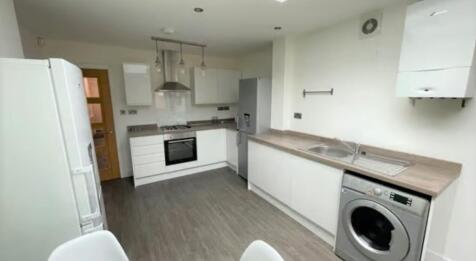 Modern kitchen featuring white cabinetry, a sta...