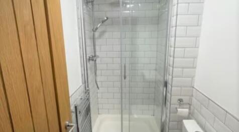 A modern bathroom featuring a glass-enclosed sh...