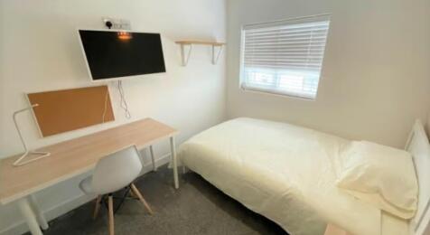 A neatly arranged single bedroom featuring a co...