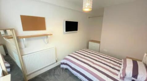 A cozy single bedroom featuring a neatly made b...