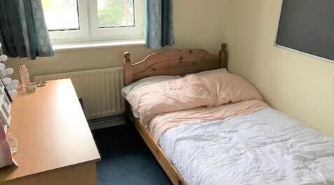 Cozy single bedroom featuring a wooden bed fram...