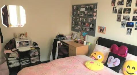 A cozy single bedroom featuring a neat study de...