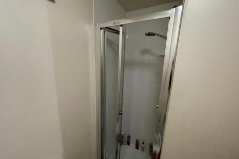 Compact bathroom featuring a modern glass showe...
