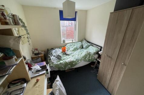 Cozy single bedroom featuring a leafy patterned...