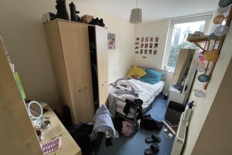 A cozy single bedroom featuring a large window ...