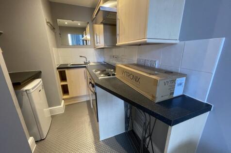 A compact, modern kitchen featuring light wood ...