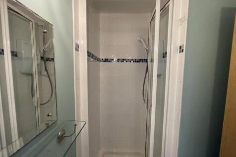Compact bathroom featuring a tiled shower enclo...