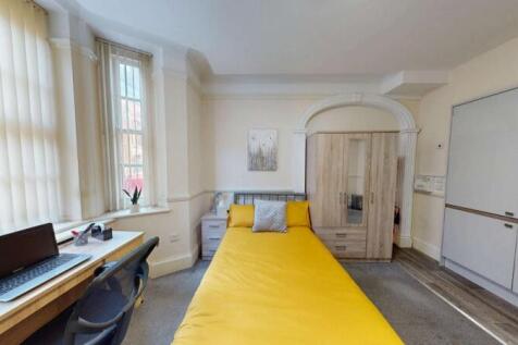 Bright single bedroom featuring a cozy bed with...