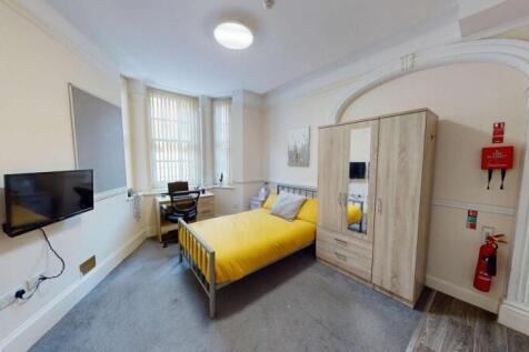 A cozy single bedroom featuring a bright yellow...