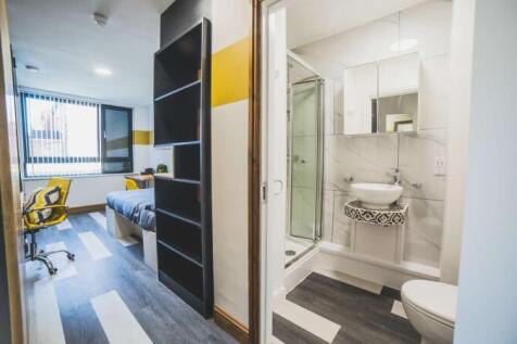 A modern and tidy single bedroom with a desk an...