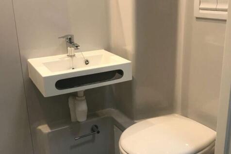 Compact and modern single toilet featuring a wa...