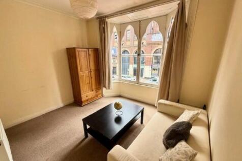 A cozy living room featuring a large bay window...