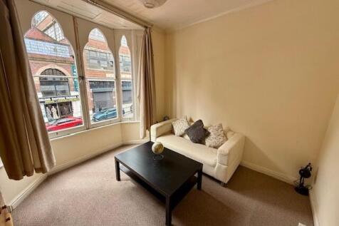 Bright living room featuring a large bay window...
