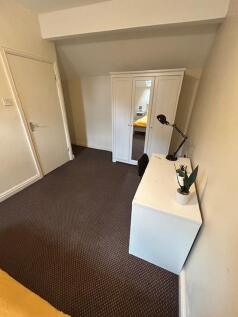 A tidy bedroom featuring a white wardrobe with ...