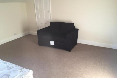 A simple bedroom space featuring a dark armchai...