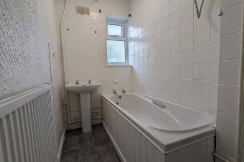 A bright bathroom suite featuring a white batht...