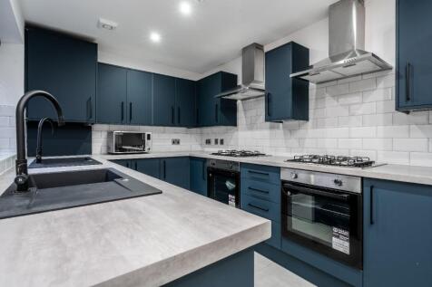 A modern kitchen featuring sleek navy cabinets,...