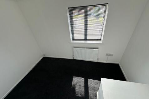 A small, clean room with a window fitted with b...