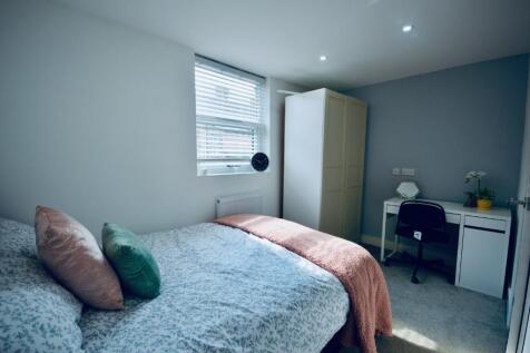 This cozy double bedroom features ample natural...