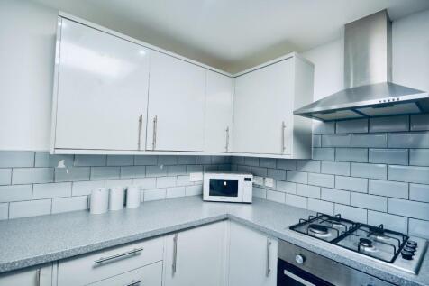 Modern kitchen featuring sleek white cabinetry,...