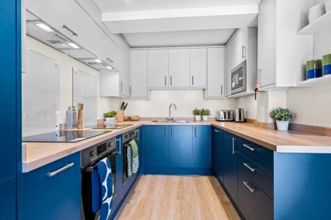 A modern kitchen featuring sleek blue lower cab...