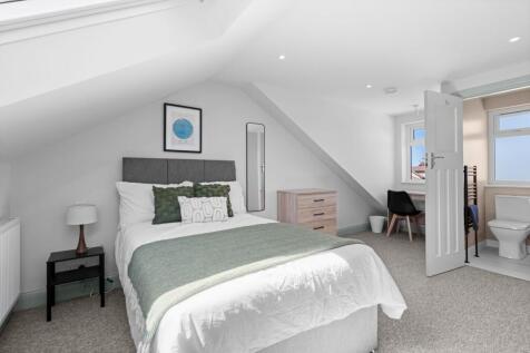A bright, modern master bedroom featuring a com...