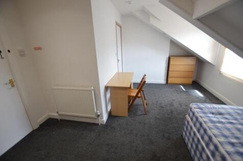 A cozy single bedroom featuring a slanted ceili...