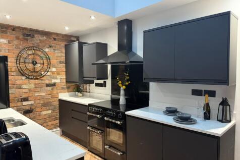 A modern and stylish kitchen featuring sleek bl...