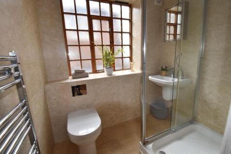 A modern bathroom suite featuring a glass-enclo...