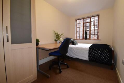 Cozy single bedroom featuring a practical study...