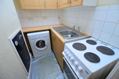 Compact kitchen featuring wooden cabinetry, a w...