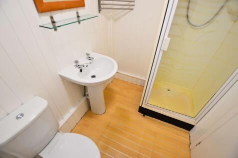 Compact bathroom featuring a clean white toilet...