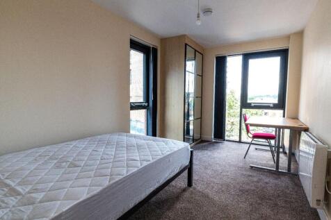 Bright single bedroom featuring large windows t...