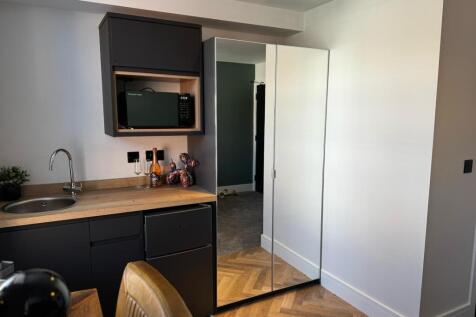 A modern kitchenette featuring sleek black cabi...
