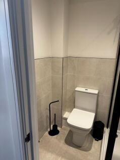 A modern and clean single toilet with beige til...