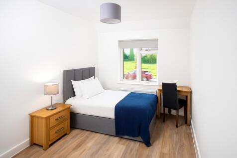 A clean and cozy single bedroom featuring a com...