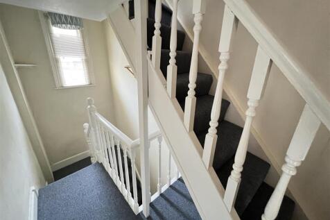 Bright and clean carpeted staircase area with w...